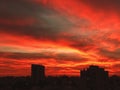 Sunset in the city with stunning colorful magic clouds. Spring sky with red clouds and roofs view. Royalty Free Stock Photo