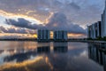 Sunset with clouds behind modern architecture apartment buildings with lake reflections