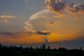 Sunset, clouds lit by the orange rays of the sun against the blue evening sky. Colorful summer landscape Royalty Free Stock Photo