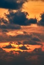 Sunset clouds in orange evening sunlight. Flaming sunset with light passing through the dark clouds. Landscape. Vertical photo. Royalty Free Stock Photo