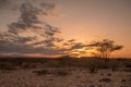 Sunset through the clouds over an arid desert landscape of sand Royalty Free Stock Photo