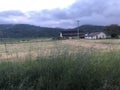 Sunset clouds over a green and brown field with farm in background. Royalty Free Stock Photo