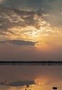 Sunset with clouds on the sky reflected on water