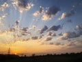 Sunset cloudy sky with picturesque clouds lit by warm sunset sunlight. Country road at sunset