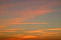 Sunset colored clouds in blue sky with contrail