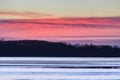 Sunset colored sky and lake with ice