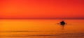 little boat in a sea red orange sky at sunset