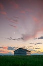 Sunset and a couple abandoned and broken down farm house in the Alberta prairies