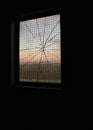 Sunset through cracked glass of an antivandal reinforced industrial window Royalty Free Stock Photo