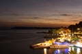 Sunset in croatian resort Podgora, last beams of sun and colorful city illumination.