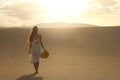 Sunset in the desert. Young woman with white dress walking in the desert dunes with footsteps in the sand during sunset. Girl Royalty Free Stock Photo