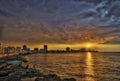 Sunset and dramatic clouds over Havana skyline with fishermen in foreground Royalty Free Stock Photo