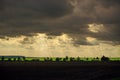 Sunset with dramatic cloudscape over agricultural field and road with cars and trucks Royalty Free Stock Photo