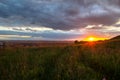 Sunset in dramatic cloudscape over wild herb field with distant city in view Royalty Free Stock Photo