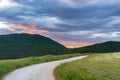 Sunset dramatic sky over country road in Marche region, Italy. Epic clouds above winding trail unique hills and mountains