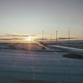 Sunset dusk shining on a snowy landing airport track seen from an airplane window Royalty Free Stock Photo