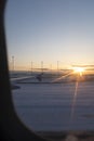 Sunset dusk shining on a snowy landing airport track seen from an airplane window