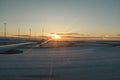 Sunset dusk shining on a snowy landing airport track seen from an airplane window Royalty Free Stock Photo