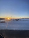 Sunset dusk shining on a snowy landing airport track seen from an airplane window