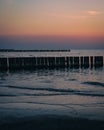 Sunset on an empty beach with wooden breakwaters. Royalty Free Stock Photo