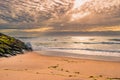 Sand with algae of stones piled with moss where the sea breaks at sunset on Esposende beach PORTUGAL Royalty Free Stock Photo