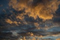 Sunset evening blue sky with fluffy airy orange yellow clouds in light of sun against a background of dark clouds Royalty Free Stock Photo