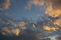 Sunset evening gradient blue sky with different shapes fluffy light orange yellow clouds against a background of dark clouds Royalty Free Stock Photo