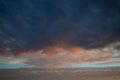 Sunset evening sky with pink and light orange, textured dark blue clouds Royalty Free Stock Photo