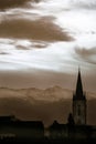 Sunset in a foggy mystic scenery with clouds and a mountain silhouette with a church tower in the austrian alps