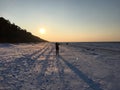 The sunset on a frosty clear evening and a girl on a walk photographs it. Jurmala, Latvia, January 3, 2018