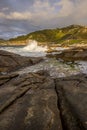 Sunset on the Galician coast of the lower estuaries next to large breakwaters of granodiorite rocks with waves hitting the coast Royalty Free Stock Photo