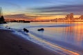 Sunset glow and city lights reflecting over river water and beach Royalty Free Stock Photo