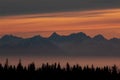 Sunset glow over mountain peaks in a foggy bay.