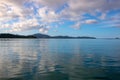 Sunset golden hour on tropic seaside. Cloudy sky reflections in rippled sea water. Tropical island in still sea Royalty Free Stock Photo