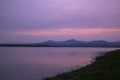 Sunset with golden magenta orange sky with mountains in the background and reflection in the water Royalty Free Stock Photo