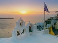 Sunset with greek flag and church bells at oia, santorini Royalty Free Stock Photo