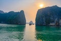 Sunset in Ha Long Bay, Vietnam. Boats, rock formations, misty mood, sunset and reflections in the South China Sea, Vietnam