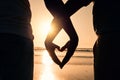 Sunset, heart hands and couple on the beach while on a vacation, adventure or weekend trip. Romance, silhouette and Royalty Free Stock Photo