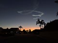 Sunset highlighting a space launch contrail against the silhouettes of a neighborhood