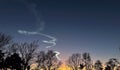 Sunset highlighting a space launch contrail against the silhouettes of a neighborhood