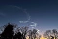 Sunset highlighting a space launch contrail against the silhouettes of a neighborhood