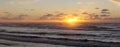 Sunset at Hokitika beach with clouds and golden sky on the South Island of New Zealand.