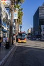 Sunset on Hollywood Blvd with people walking, a Gold Coast Tour bus and cars driving on the street with palm trees in Hollywood