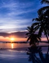 Sunset by infinity pool, silhouette of palm trees and reflection on water Royalty Free Stock Photo