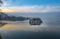 Sunset on Ioannina town. Small wooden boat floating the calm waters on lake Pamvotis and transfer passengers to a very small