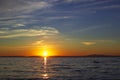 Sunset on Lake Baikal in dark moody colors, sun sets over the horizon above calm waves and 2 gulls on stone in the water Royalty Free Stock Photo