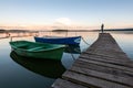 Sunset on the lake with boats and a girl standing on the pier Royalty Free Stock Photo