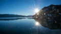 Sunset at lake shore Walchensee, bright sun with rays, flares and water reflection Royalty Free Stock Photo