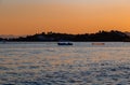 Sunset, lake sparkling. Fishermen driving a small fishing boat in fishing. Royalty Free Stock Photo