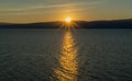 Sunset on the lake. The sun sets behind the mountains, the reflection of rays on the water surface Royalty Free Stock Photo